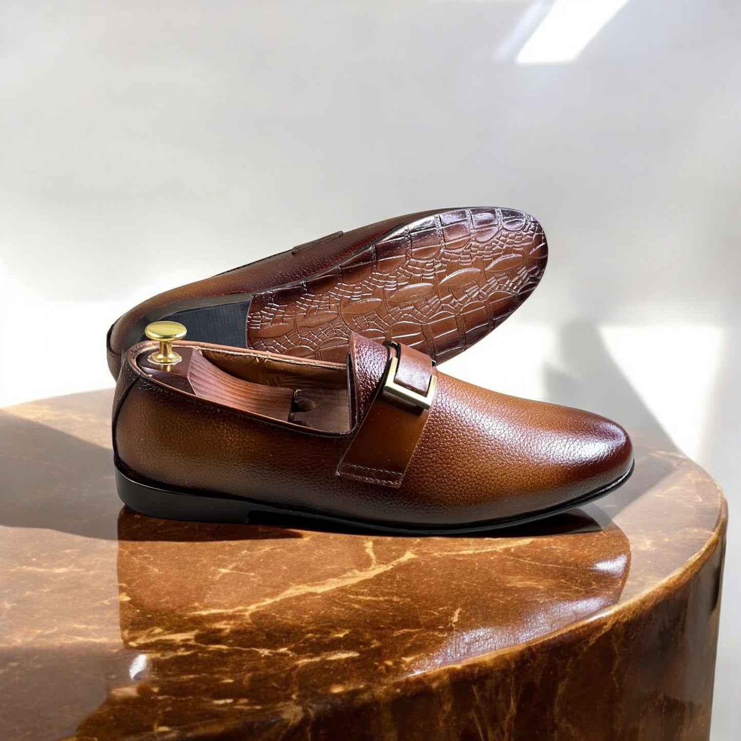 These elegant brown leather loafers are crafted from high-quality full-grain leather with a rich, dual-tone gradient finish. Featuring a sleek slip-on design, they offer both sophistication and comfort. The shoes are adorned with a stylish metal-buckled strap, adding a refined touch to their classic silhouette. 

The interior is lined with premium leather for breathability and durability, while the cushioned insole ensures all-day comfort. The sturdy black outsole provides excellent grip and longevity. Idea