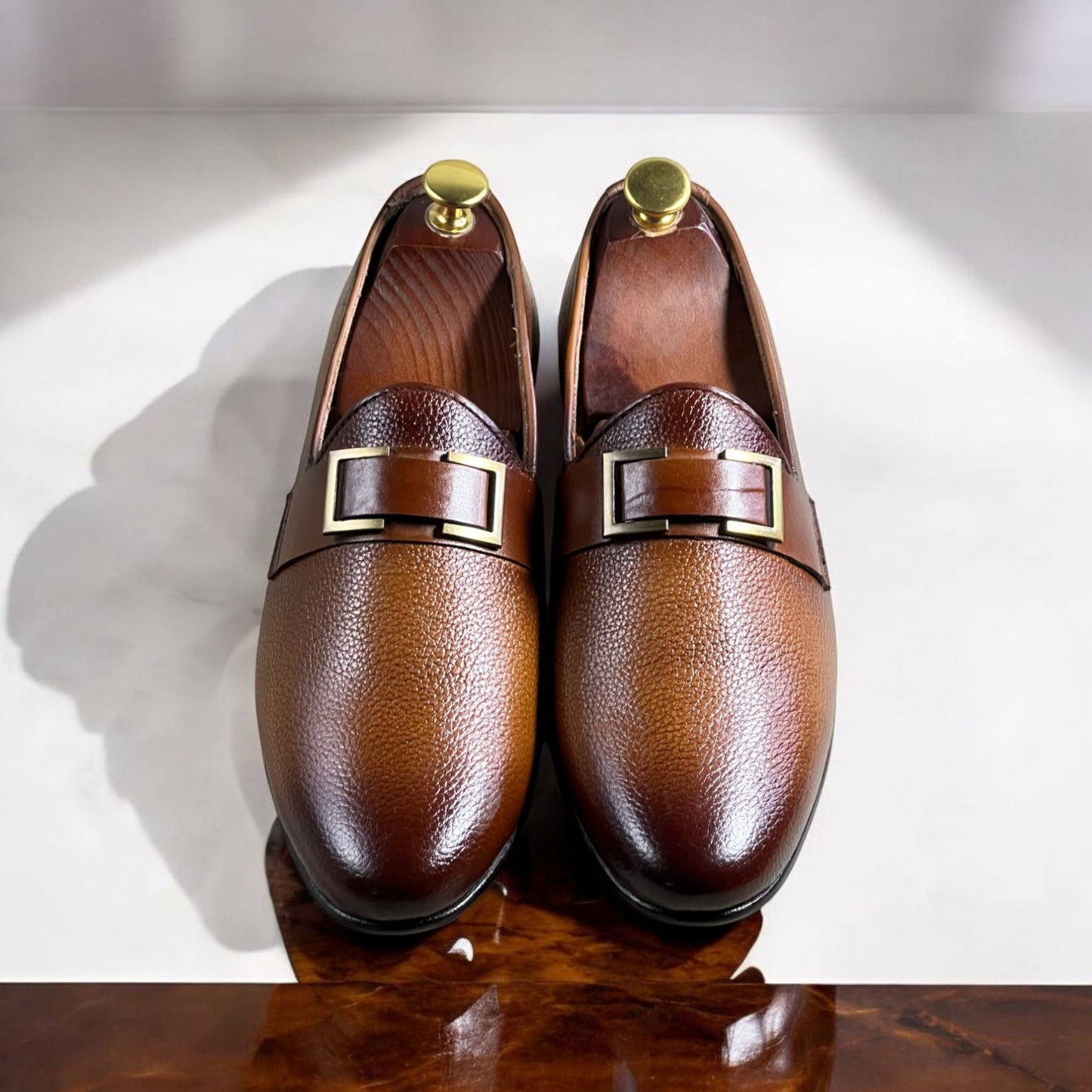 These elegant brown leather loafers are crafted from high-quality full-grain leather with a rich, dual-tone gradient finish. Featuring a sleek slip-on design, they offer both sophistication and comfort. The shoes are adorned with a stylish metal-buckled strap, adding a refined touch to their classic silhouette. 

The interior is lined with premium leather for breathability and durability, while the cushioned insole ensures all-day comfort. The sturdy black outsole provides excellent grip and longevity. Idea